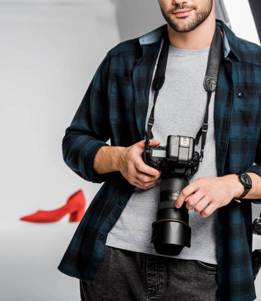 cropped shot of professional young photographer holding camera in photo studio cropped shot of professional young photographer holding camera in photo studio